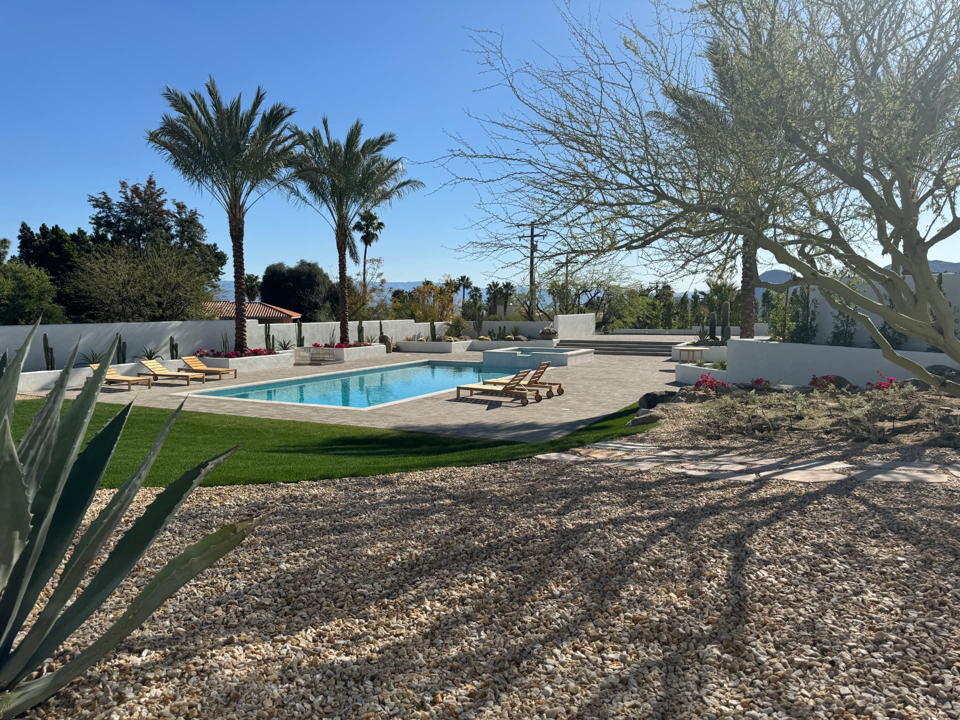 Modern desert estate with a rectilinear pool, white plaster walls, palms and gravel garden